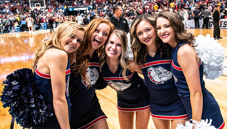 A group of female cheerleaders smiles for the camera. 