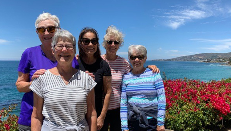 five women standing near the ocean