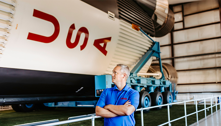 Richard Koelsch standing next to spaceship in hangar.