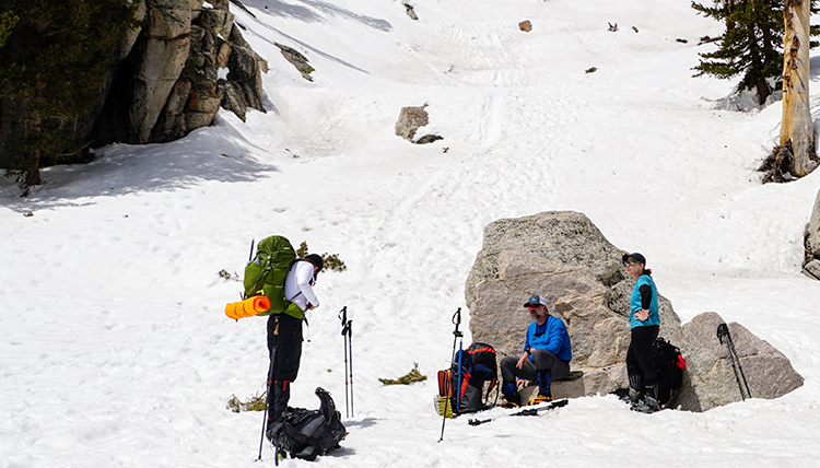 hikers rest on a rock in the snow on the mountain side