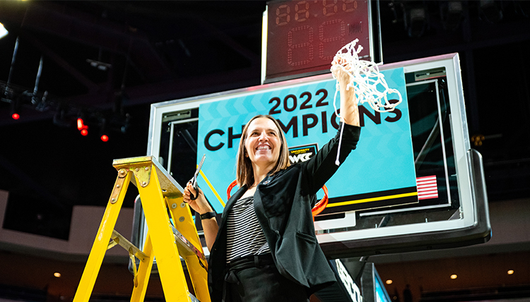 coach lisa fortier cutting the net at the 2022 WCC tourney