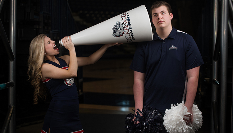 cheerleader yelling through bullhorn to bored brother