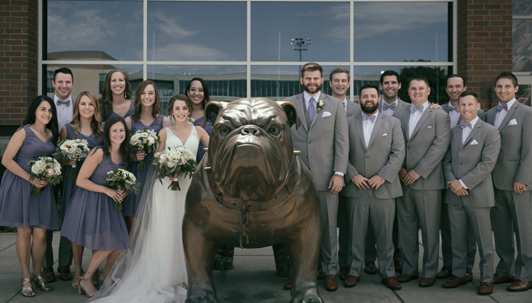 large group with wedding couple around Bulldog statue