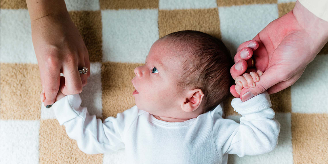 baby holding fingers of parents