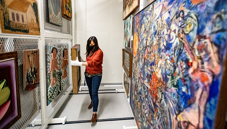 women in the stacks of carefully stored artwork
