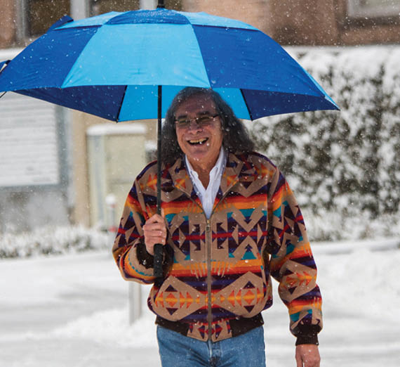 Reyes walks with umbrella through a snowy campus 