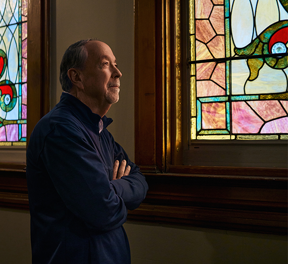 Chuck Murphy posed near stained glass windows