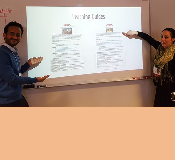 Two graduate teaching students show off their work on a slide. 