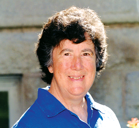 Woman (Sister Mary Garvin) with short, dark hair and a blue, collared shirt smiling. 