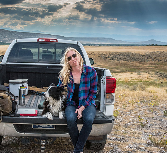 Alexis Bonogofsky sits on the back of her truck with her dog. 