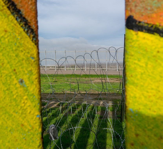 A chain link fence is visible through sections of the border fence. 