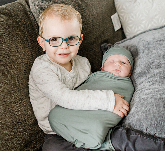 toddler boy holds baby sibling