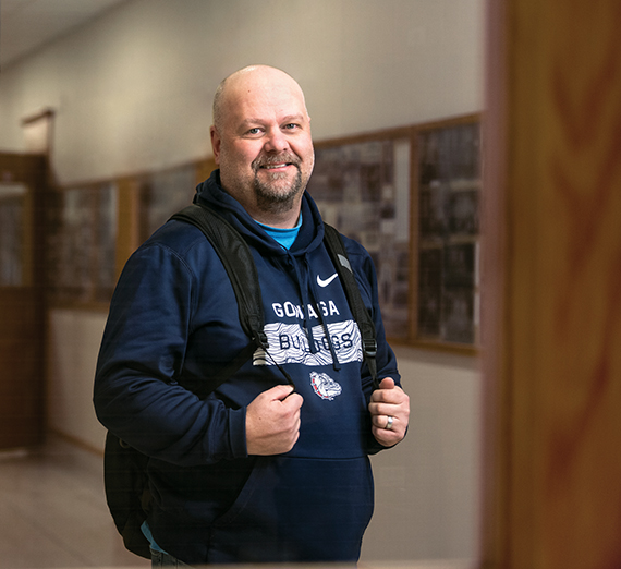 Rick Clark stands with a backpack in a hallway.