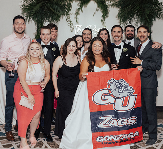 Hoeing and Rossi holding a Gonzaga flag at their wedding with guests.