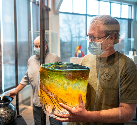 man handling a glass work by Dale Chihuly 