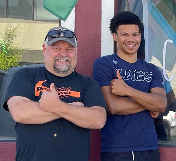 two smiling men with thumbs up