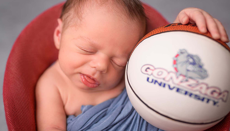 A baby poses with a GU basketball