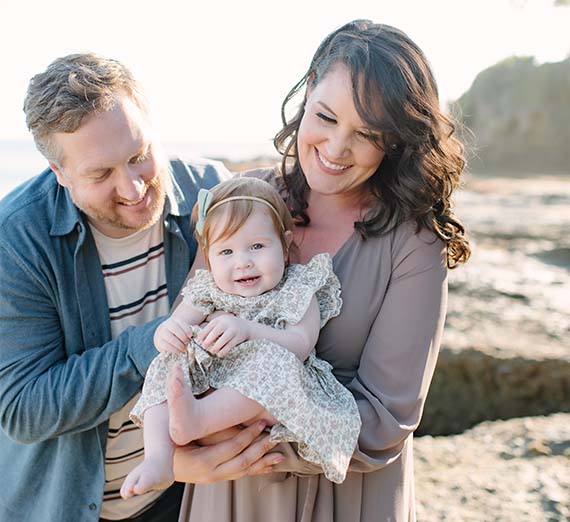 Parents pose with their child at the beach