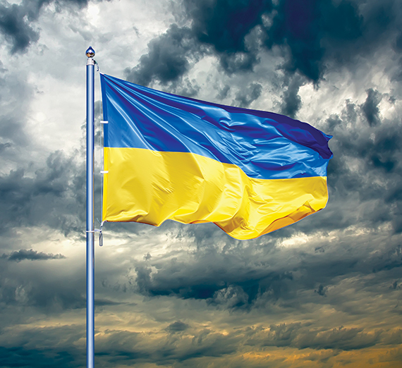 The Ukraine flag flies against a grey sky.