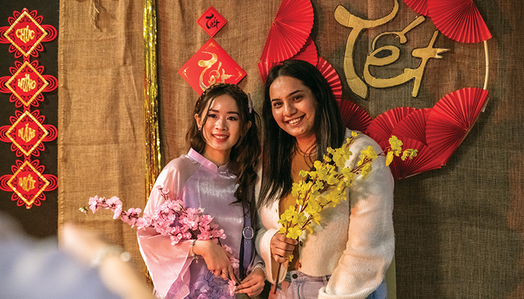 two women in front of a colorful Vietnamese Tet background