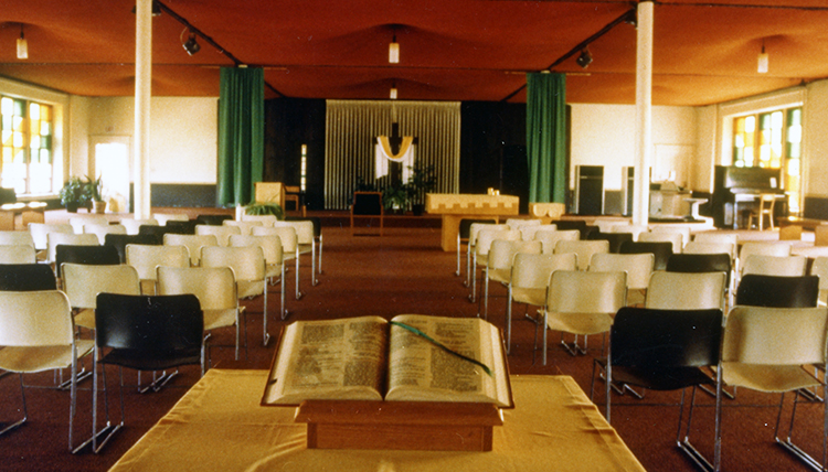 the chapel with plastic chairs and a burlap ceiling