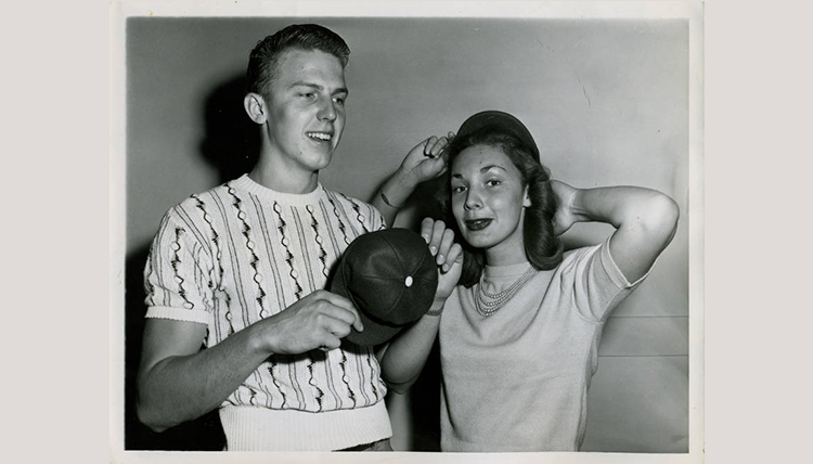 black and white image of male and female students trying on beanies