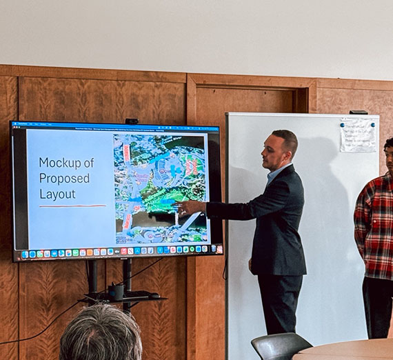 Male student wearing suit pointing to an on-screen presentation