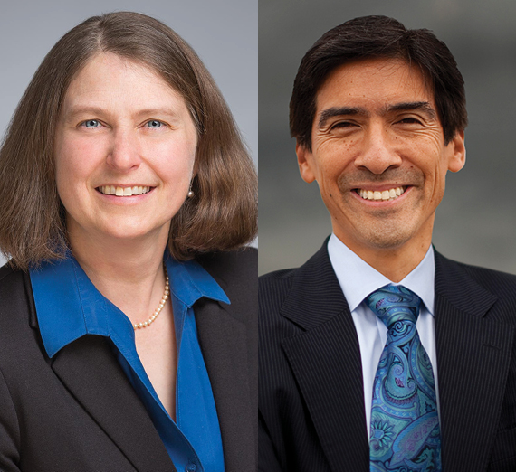 A female student in graduation cap and gown holds her degree over her head. 
