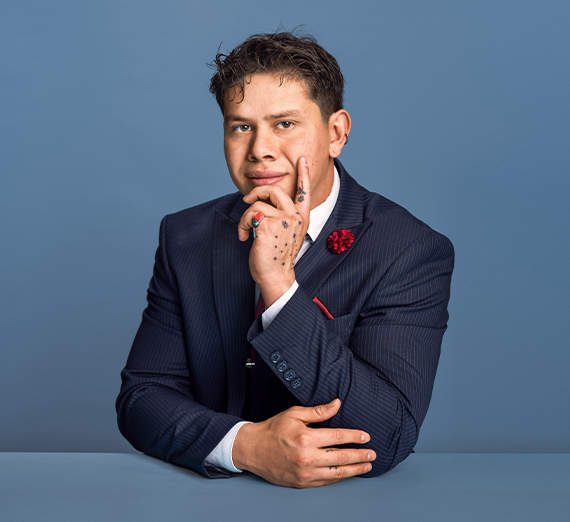 Kiko Macias (’25 J.D.) wearing a dark suit and sitting with one hand resting on his chin.
