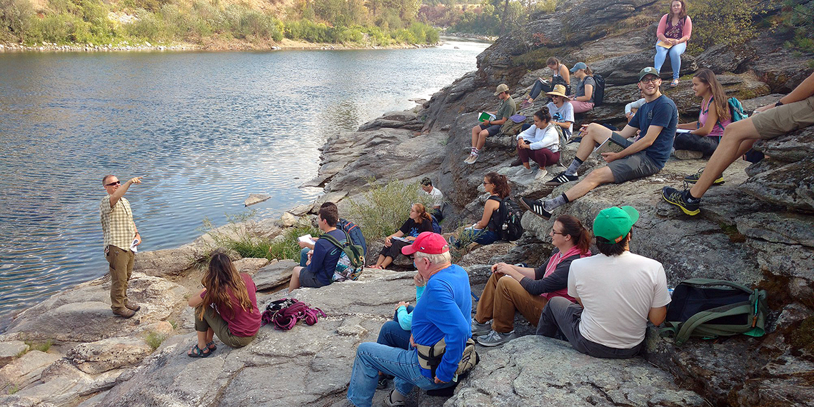 Jerry White, executive director of Spokane Riverkeeper, offers a guest lecture about water quality on the banks of the Spokane River for a field trip in an environmental studies course taught by Greg Gordon, associate professor of environmental studies. (Photo courtesy Greg Gordon)