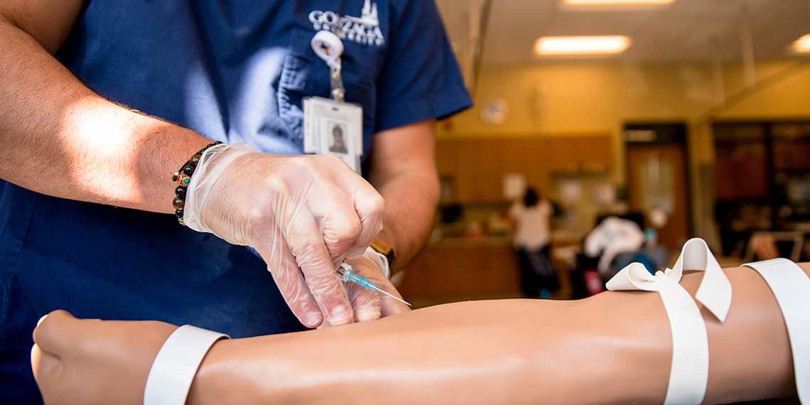 A student practices injections on a mannequin. (GU photo)