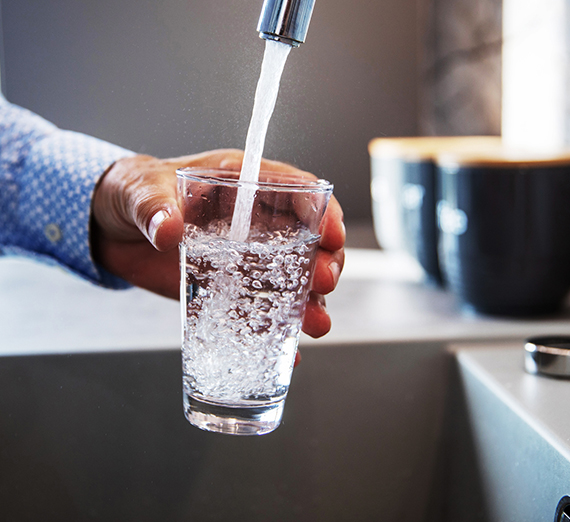 Glass of water being filled in the sink.