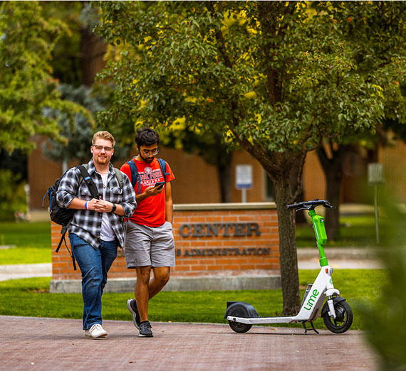Two male students walk along Bulldog Alley and an electric scooter sits nearby