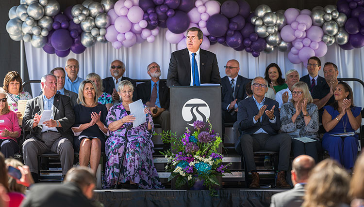 Gonzaga President Thayne McCulloh speaking at a podium, surrounded by visiting dignitaries