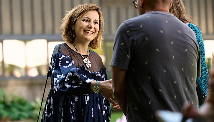 President Katia Passerini shakes hands with a parent while smiling