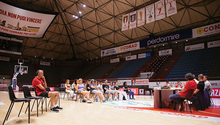 Gonzaga students sit on a basketball court floor in Italy