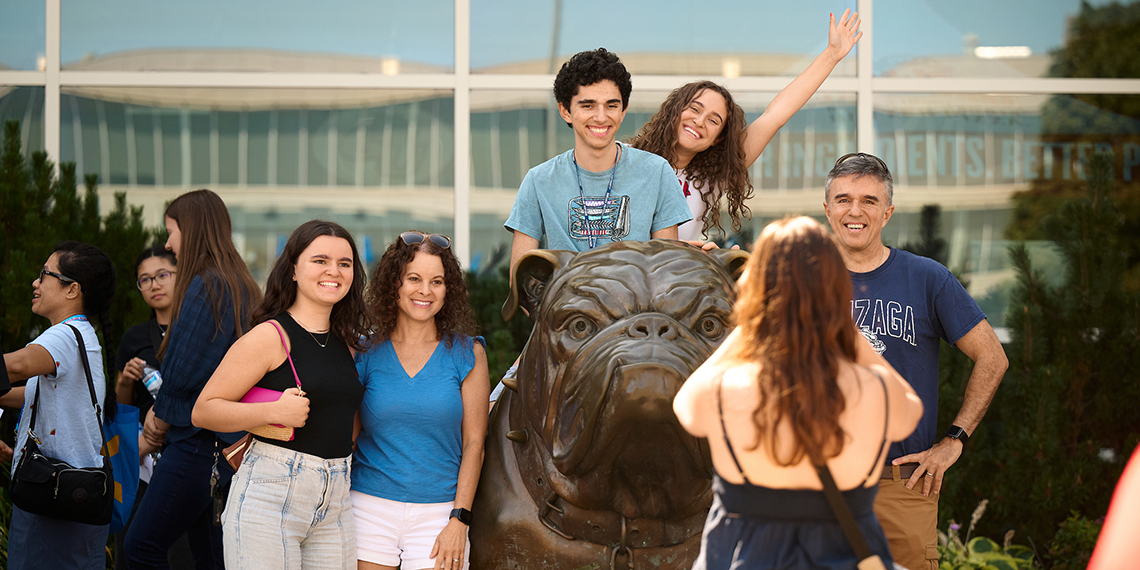 A family poses for photos near a statue of a bulldog