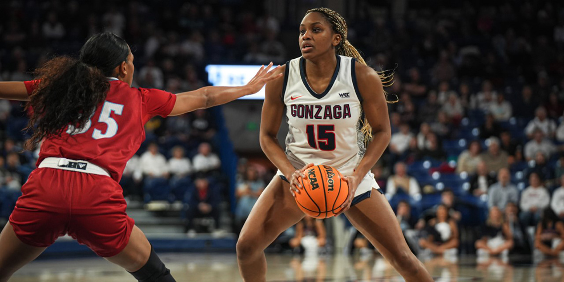 Women's basketball player Yvonne Ejim holds the ball while a defender approaches her on the court.