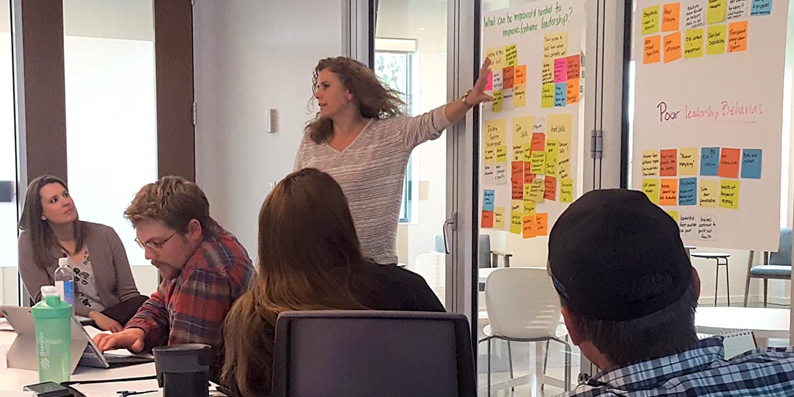 A presenter points to sticky notes on large sheets of paper as part of class in Gonzaga's Design Thinking certificate program.