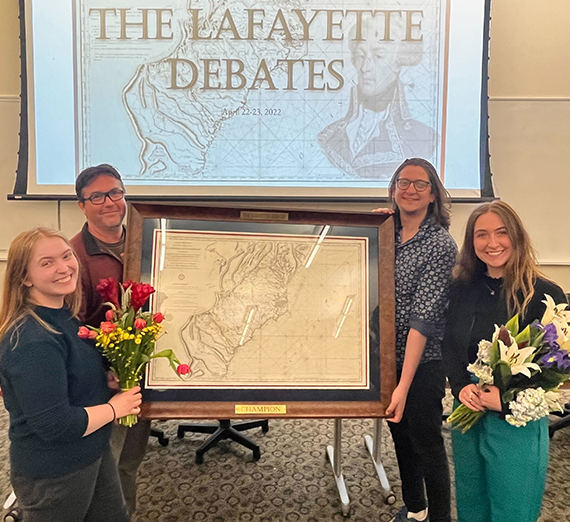 Gonzaga University debate coach Glen Frappier, left, and assistant coach Joe Skoog hold the trophy map for Lafayette Debates champions Molly Martin, left, and Avalyn Renee.