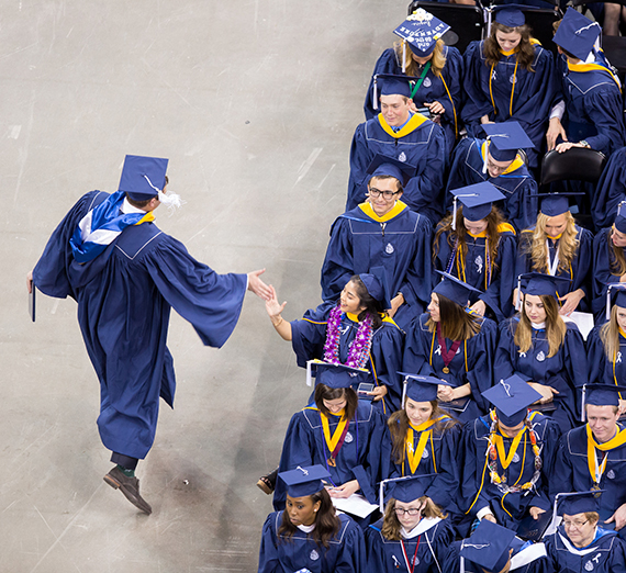 Two graduates slap a "high five" on Commencement Day