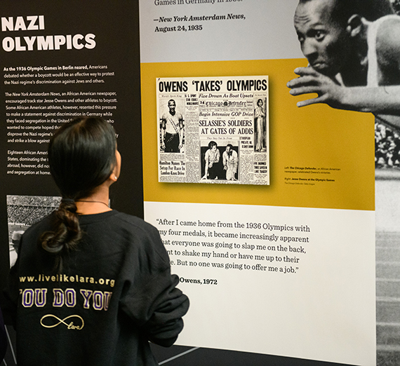 A high school student looks at a display of Jesse Owens from the Americans and the Holocaust exhibit