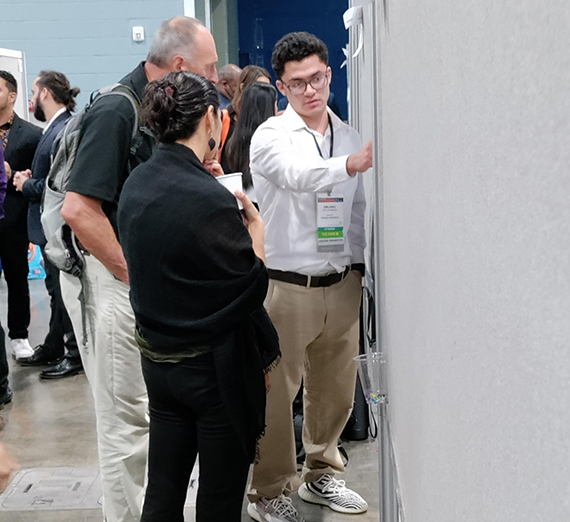 Biology senior Emiliano Soto-Romero shows a poster of his research to curious onlookers at the National Diversity in STEM conference in Puerto Rico. 