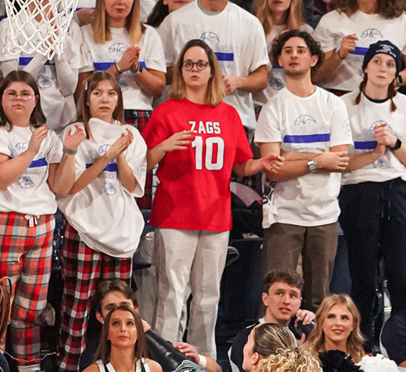 Woman in red Gonzaga t-shirt among fans cheering at basketball court