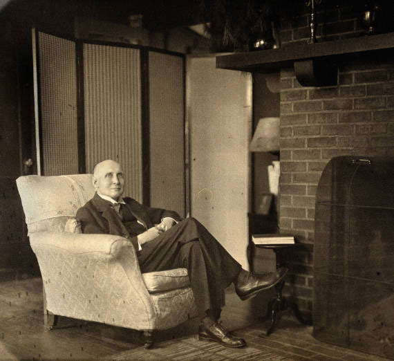 Alfred North Whitehead sitting in a chair, looking at the camera 