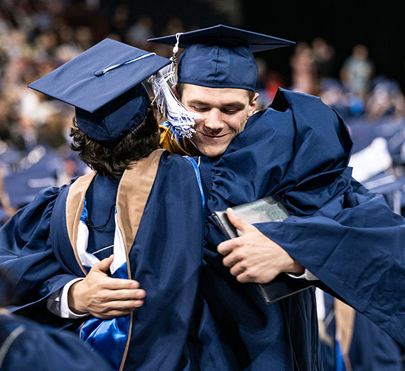 Graduating students hug each other at Commencement.