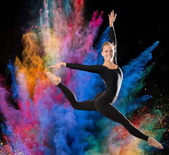 Dancer jumps in front of a colorful chalk explosion