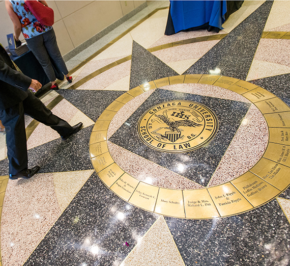People walking past the law school logo embedded in the floor 