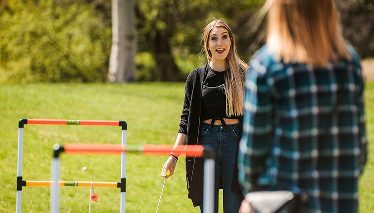 Female students playing a game of ladder toss in a field