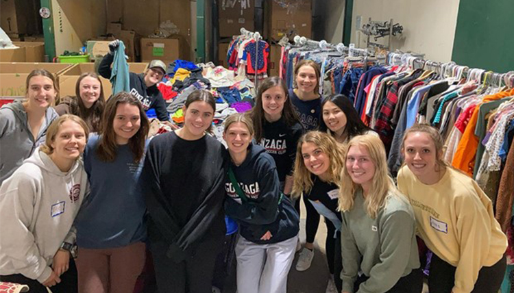 13 Gonzaga Students pose for a photo at the Global Neighborhood thrift clothes sorting room. 